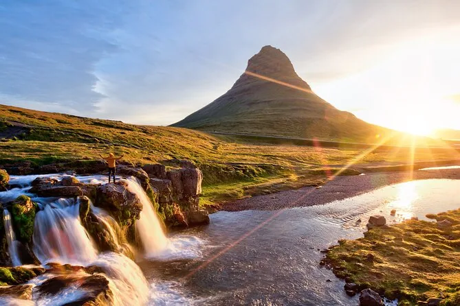 Kirkjufell and its waterfall with the sun low on the horizon